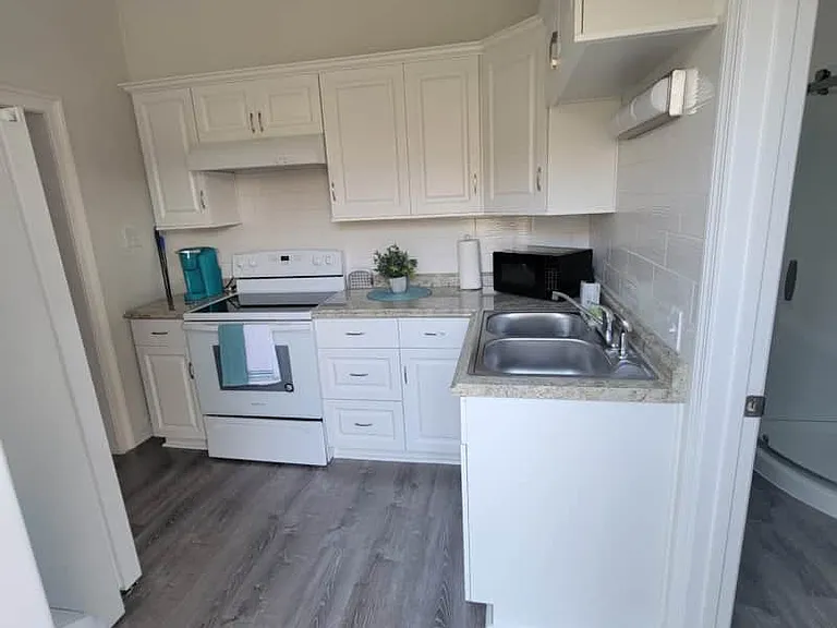Kitchen includes a coffee maker, microwave, sink, stove with oven, and range hood.