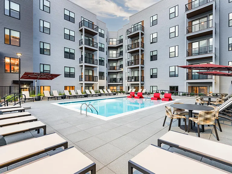 A vibrant pool courtyard with shaded seating and lounge chairs at Modera LoSo.