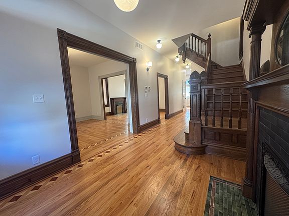 Grand entry foyer with views of restored historic staircase, living room, and dining room, with custom-matched inlaid floors