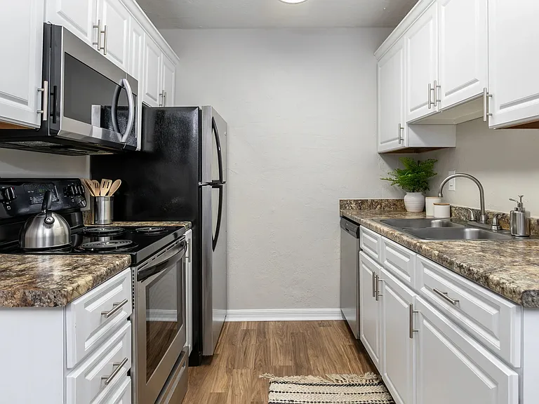 Experience timeless elegance in our updated kitchens, featuring white cabinetry, granite-inspired countertops, and wood-style flooring.