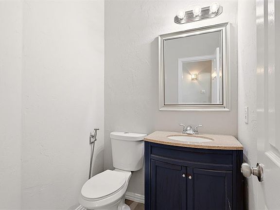 Powder room featuring a dark wood-finish vanity with a light-toned countertop, an undermount sink, and a framed mirror