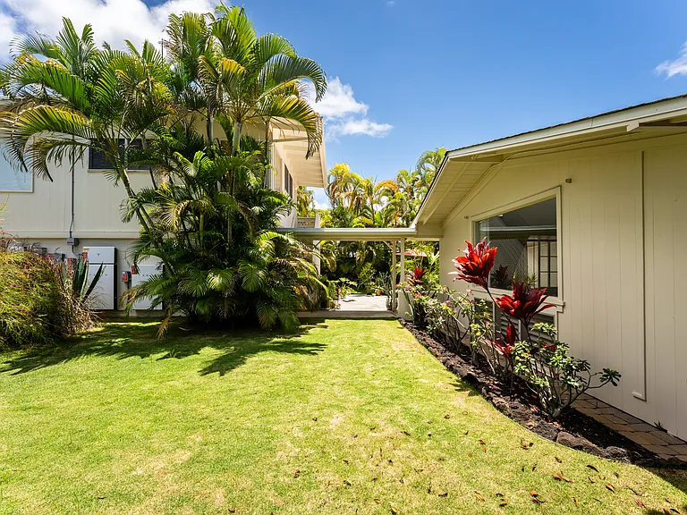 Lush landscaped lawn area separating the main home and detached cottage, creating a private and peaceful outdoor setting with mature tropical landscaping throughout.