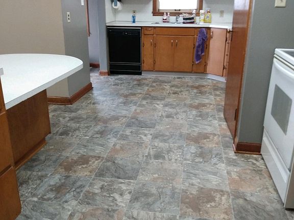 Kitchen. Refrigerator and stove to the right, dishwasher and sink center, built in table to the left.