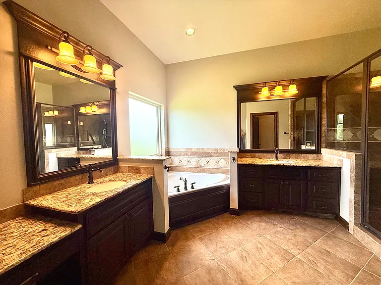 Enter into your gorgeous Master Bathroom. Double sink vanities on separate walls divided by a large corner tub. To the right is your walk-in shower with grab bars. Toilet is behind you in its own water closet. A tall storage cabinet is to the left.