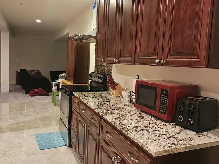 Galley-style kitchen with granite-look counters, ample upper and lower cabinetry, and full-size range with vent hood.