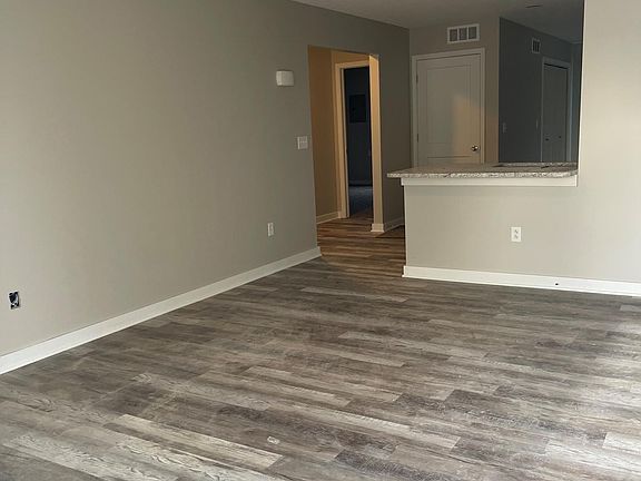 Large Living room with wood-look luxury vinyl plank floors opens up to kitchen/dining area
