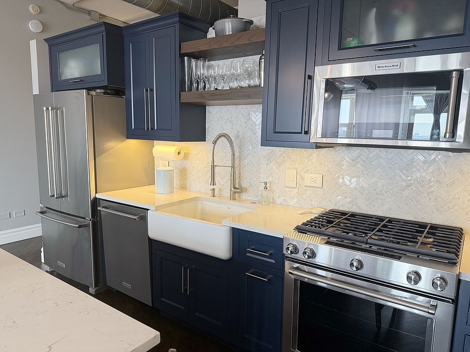 KitchenAid appliance suite, quartz countertops, farmhouse sink, and under-cabinet lighting
