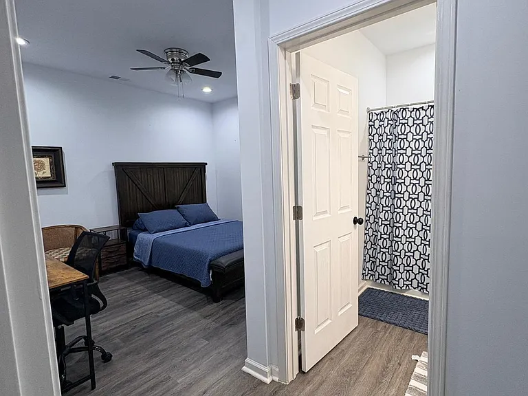 Private furnished bedroom with desk space and ceiling fan, plus convenient access to a full bath just steps away.