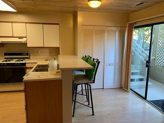 Kitchen area, barstools, beautiful sliding glass door brings in natural light.