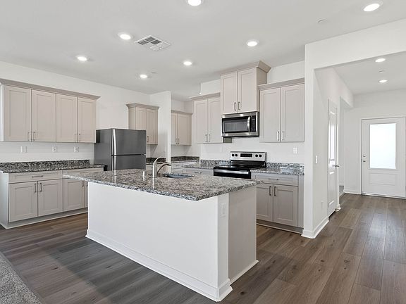The chef ready kitchen has plank flooring and stainless steel appliances.
