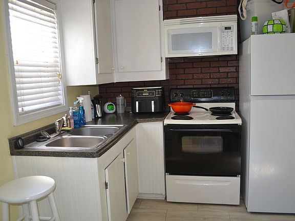 Separate kitchen with electric stove and built-in microwave oven.