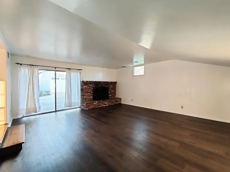Gathering room has a fireplace and large sliding door leading to rear patio.