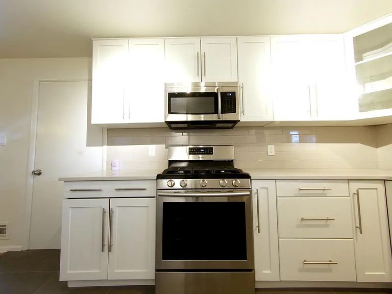 Samsung Gas Range and Microwave. The microwave features ducting to the exterior of the home. Note, door on left leads into the attached 1 car garage.