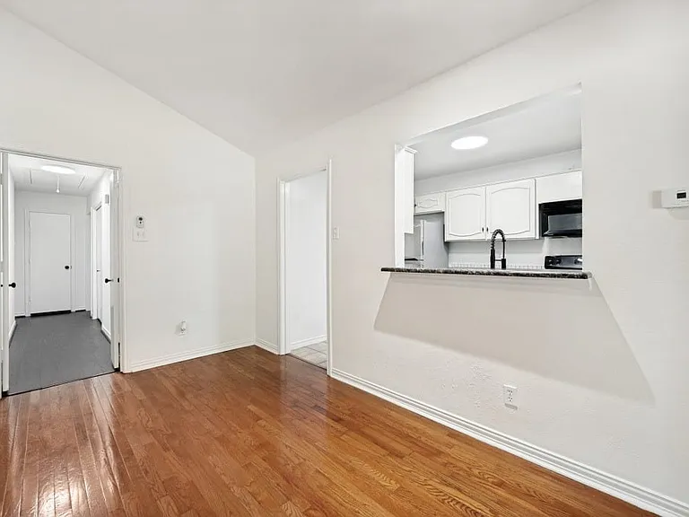 Living area featuring wood-finish flooring, white walls, and a vaulted ceiling