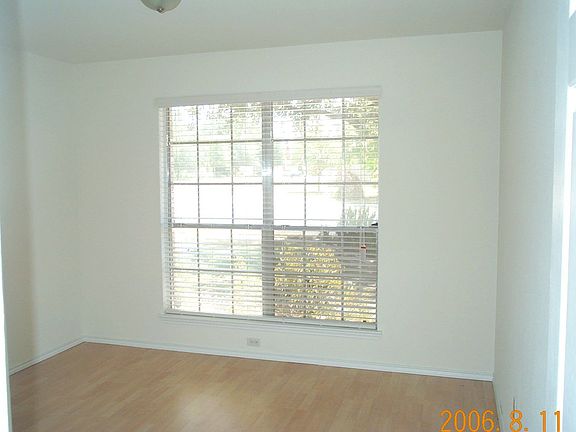 Second bedroom with picture window of front yard. Wood floors in room.