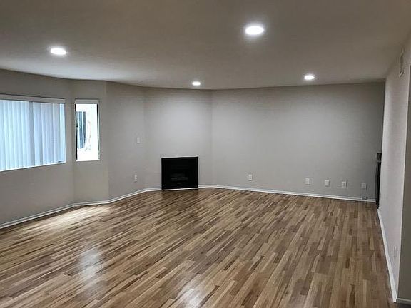 Spacious living room with wood floors. recessed lighting, and large windows to let in lots of bright light.