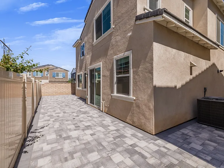 Sunny, fully paved backyard with elegant stone design featuring an AC conditioning unit and three neatly placed trash bins. Perfect for low-maintenance outdoor living, BBQs, and family gatherings in the beautiful North Menifee "Village" community.