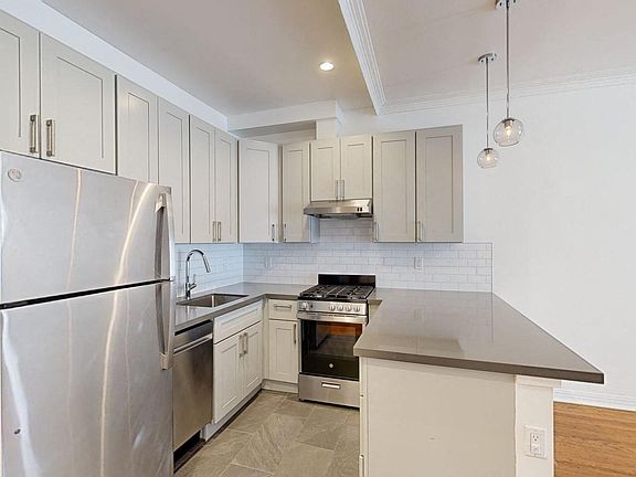 Kitchen with multiple cabinets, refrigerator, stove, range hood, and sink