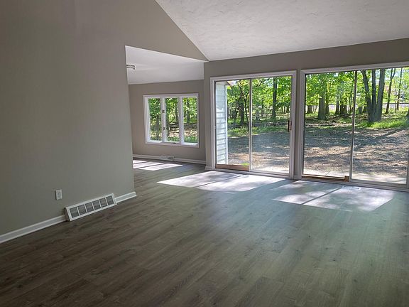 Great room with vaulted ceilings and huge slider to wooded backyard. LVT flooring throughout kitchen and living room.