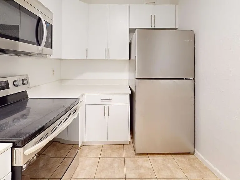 Chic modern kitchen with sleek stainless steel appliances, white cabinetry, and ceramic tile flooring.