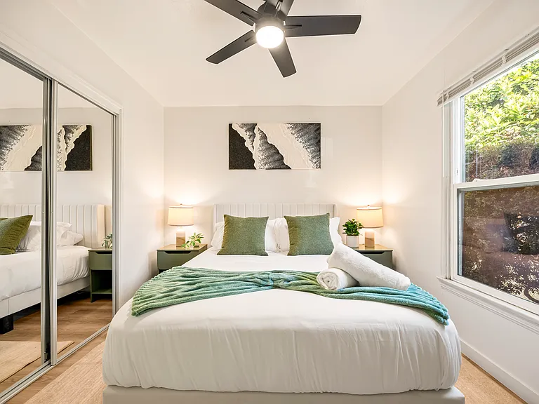 Cozy bedroom with a queen bed, ceiling fan, soft lighting, and comfortable accommodations designed for restful nights after exploring San Diego.