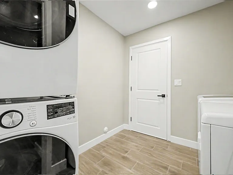 Dedicated laundry area with front-loading washer and dryer, tile flooring, and easy access off the hallway.