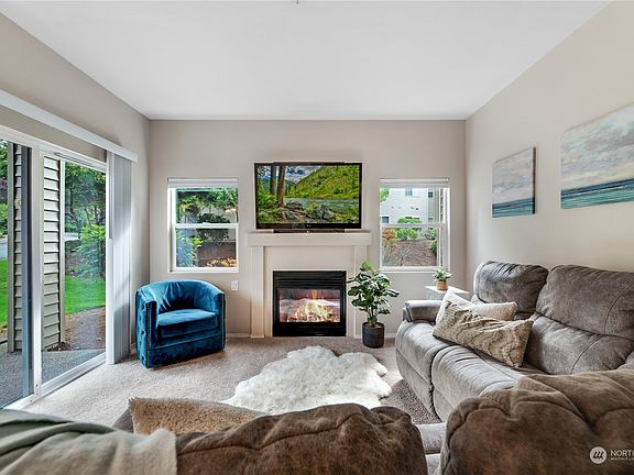The living room features a handsome gas-burning fireplace and offers an abundance of natural light. Right off the living feature is the sliding glass door to your private patio. >