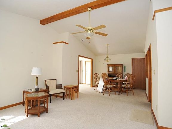 Enormous great room and dining room with vaulted ceiling and exposed wood beam.
