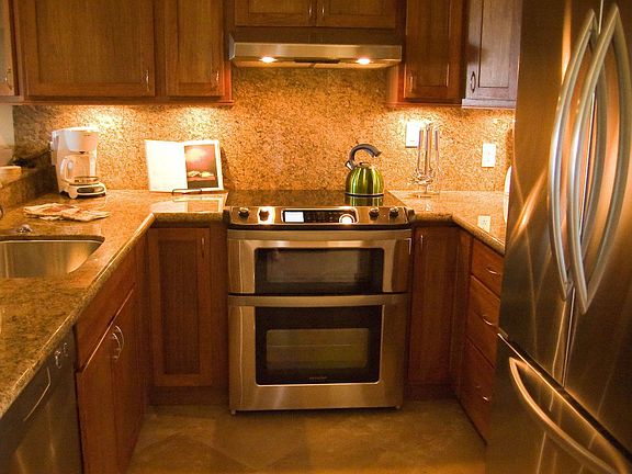 new kitchen with African hardwood cabs, stone, stainless, travertine