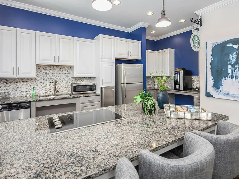 Modern clubhouse kitchen with granite countertops, stainless steel appliances, and bar seatingperfect for entertaining and resident gatherings in Charlotte.
