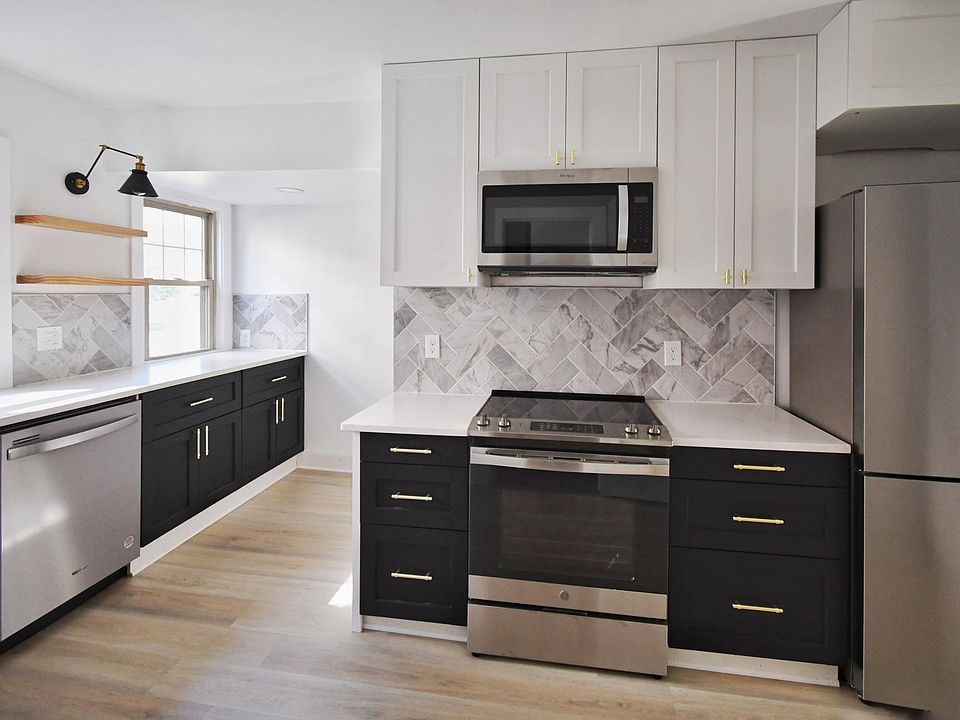 Modern kitchen with brand new stainless steel appliances including electric stove, refrigerator, microwave and dishwasher