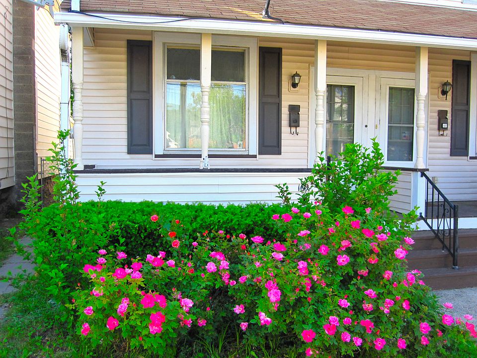 Front yard, rose bushes, full-width roofed front porch. Welcome!