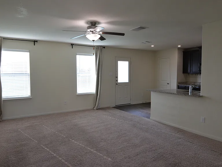 Bright open living area with abundant natural light, ceiling fan, and seamless flow into the kitchen.