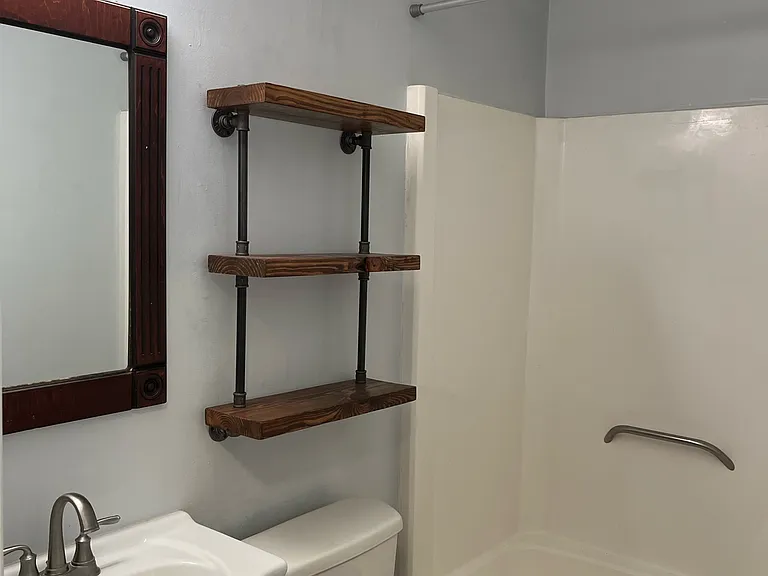 Bath with iron pipe shelving and reclaimed wood accents.