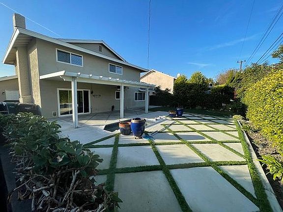 Large backyard with covered patio and oversized jacuzzi.