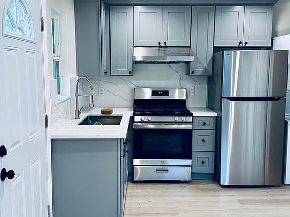 Modern open concept kitchen with brand new stainless steel appliances - Stove, oven, fridge, and stylish finishes.