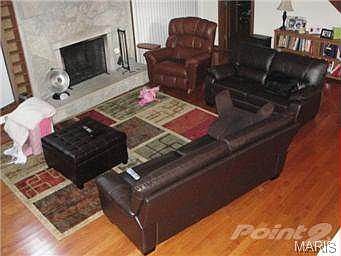 2 Story Greatroom with stone fireplace and gleaming wood floor.