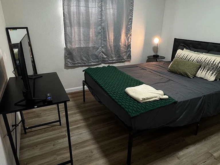 Furnished bedroom featuring a queen bed, bedside lighting, and a desk setupideal for relaxing and working from home.