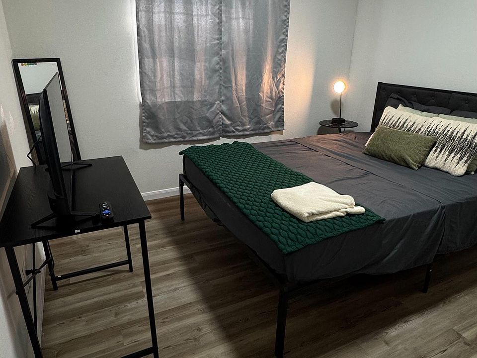 Furnished bedroom featuring a queen bed, bedside lighting, and a desk setupideal for relaxing and working from home.