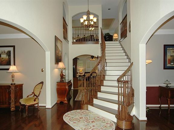 This foyer features gorgeous a chandelier, curved staircase and attractive architectural arches.