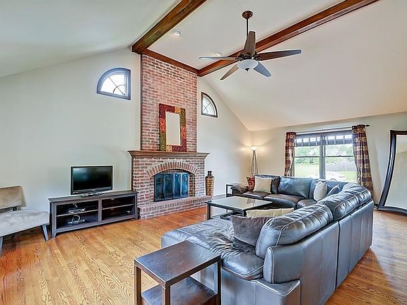 Great room features hardwood flooring, fireplace, vaulted ceiling and ceiling fan.