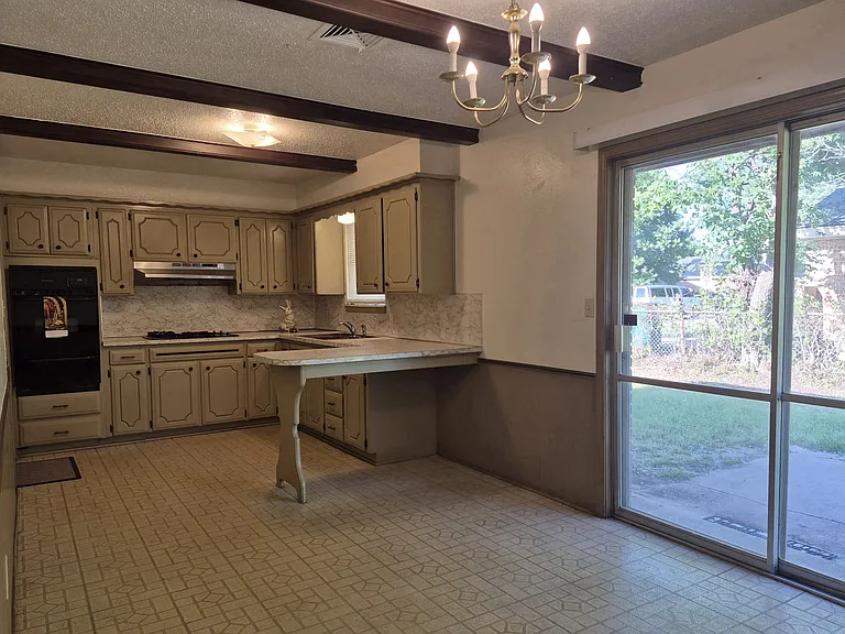 Kitchen has gas cook top and built-in oven that connects to dining area with a bar and sliding glass doors