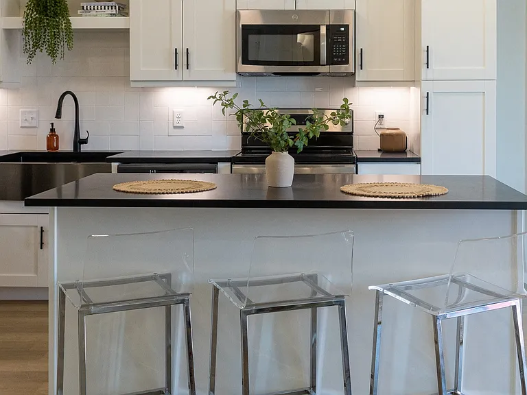 a kitchen with white cabinets and a black counter top