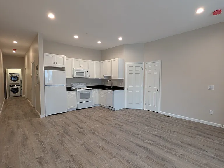 Huge living/dining room with a coat closet in the entry way that leads to a brand new kitchen with high-efficiency appliances (refrigerator, stove/oven, dishwasher, microwave)