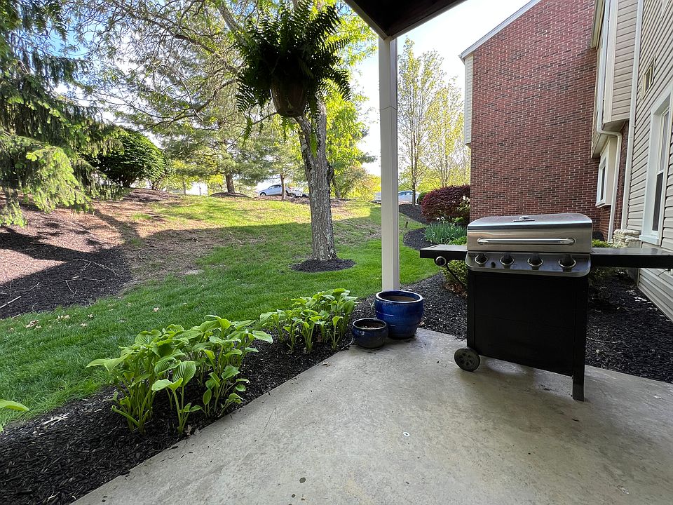 The private covered patio offers a relaxing view that is surrounded by large pines, burning bushes, and a large locus tree.