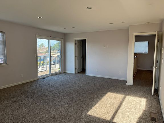 Large master bedroom with walk-in closet, balcony, master bathroom and recessed ceiling lights.