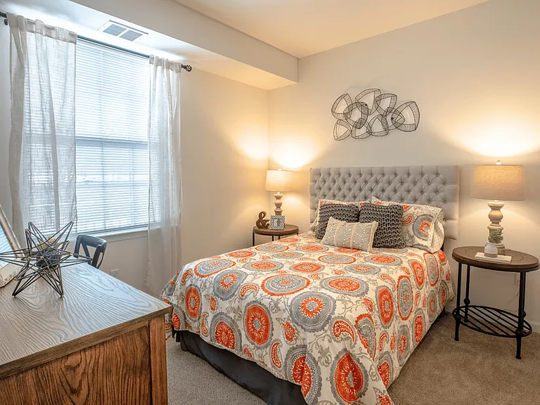 Spacious bedroom in a modern apartment featuring luxury carpeting, ample natural light, and a sleek, contemporary design for a comfortable and stylish retreat.