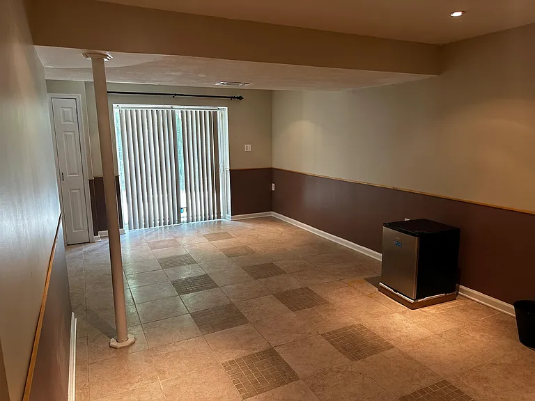 Open multi-purpose living area with tile flooring, a large sliding glass door, and a closet for convenient storage.