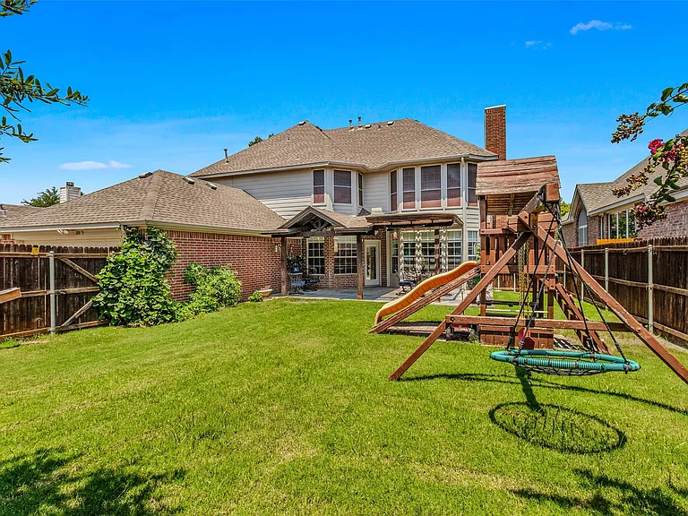 Expansive backyard featuring a manicured lawn, full privacy fencing, and a covered patio area