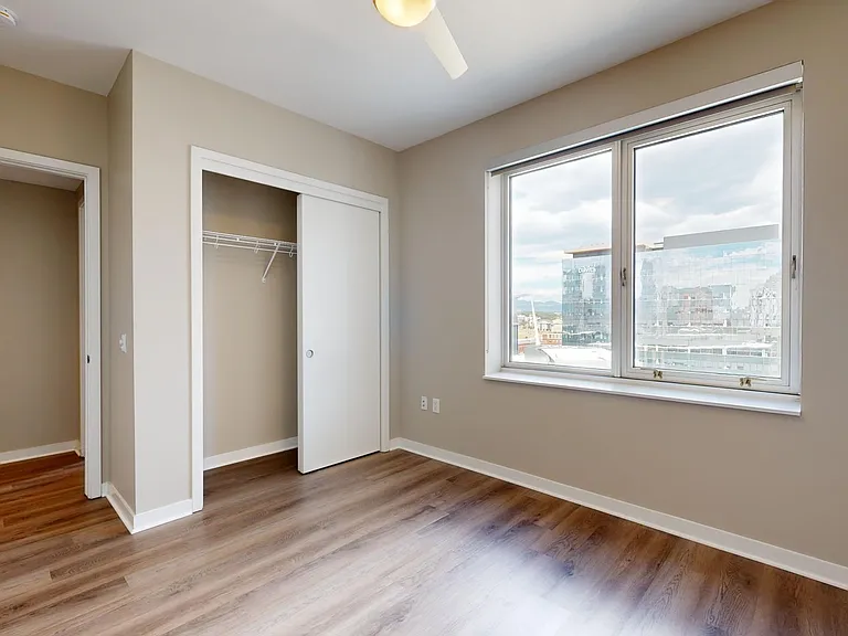 Spacious apartment bedroom with wood-style flooring.